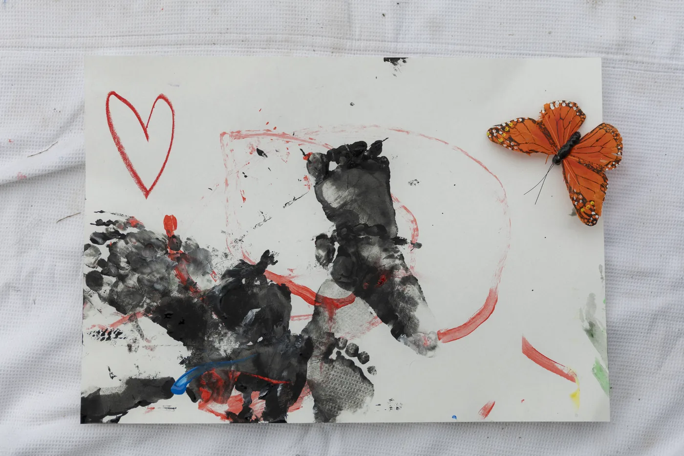 Una obra pintada con manos, un corazón y una mariposa de papel
