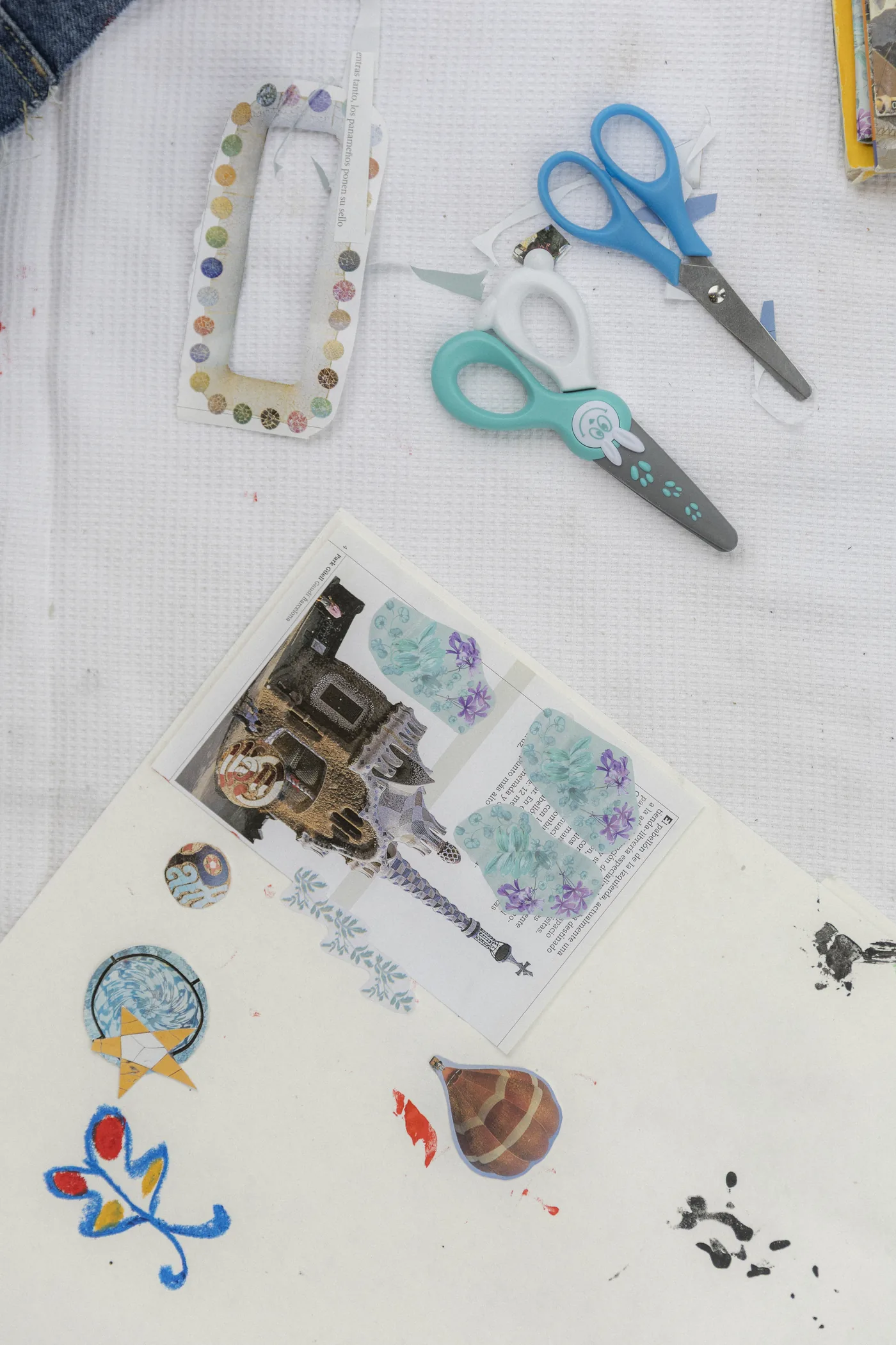 Una mesa de manualidades con tijeras, pegatinas y un collage en proceso
